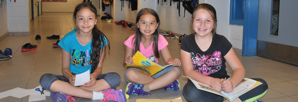 Three students working on workbooks in the school hallway